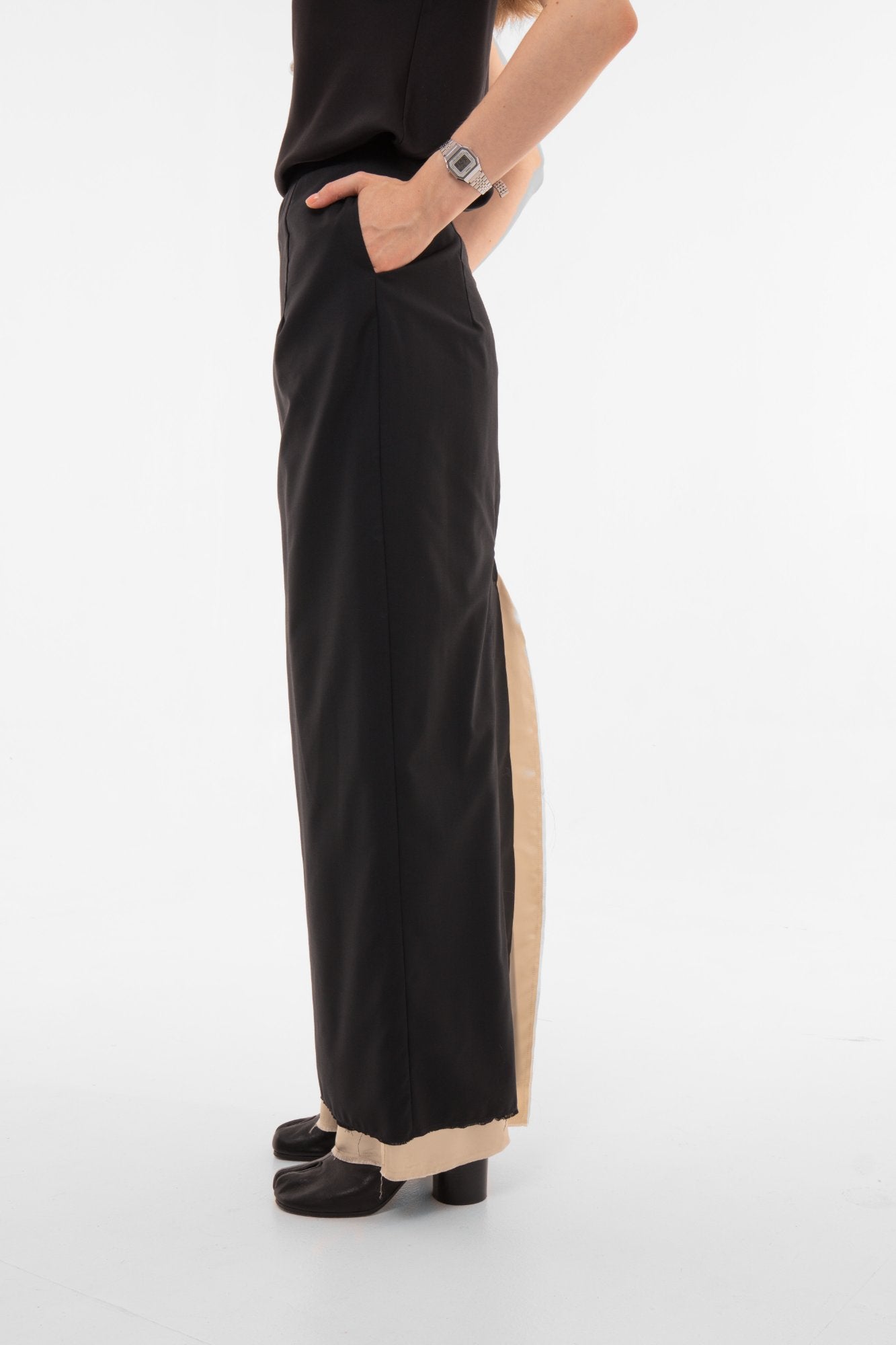 Side profile of high-waist black pencil skirt with raw-edge hem - minimalist designer piece