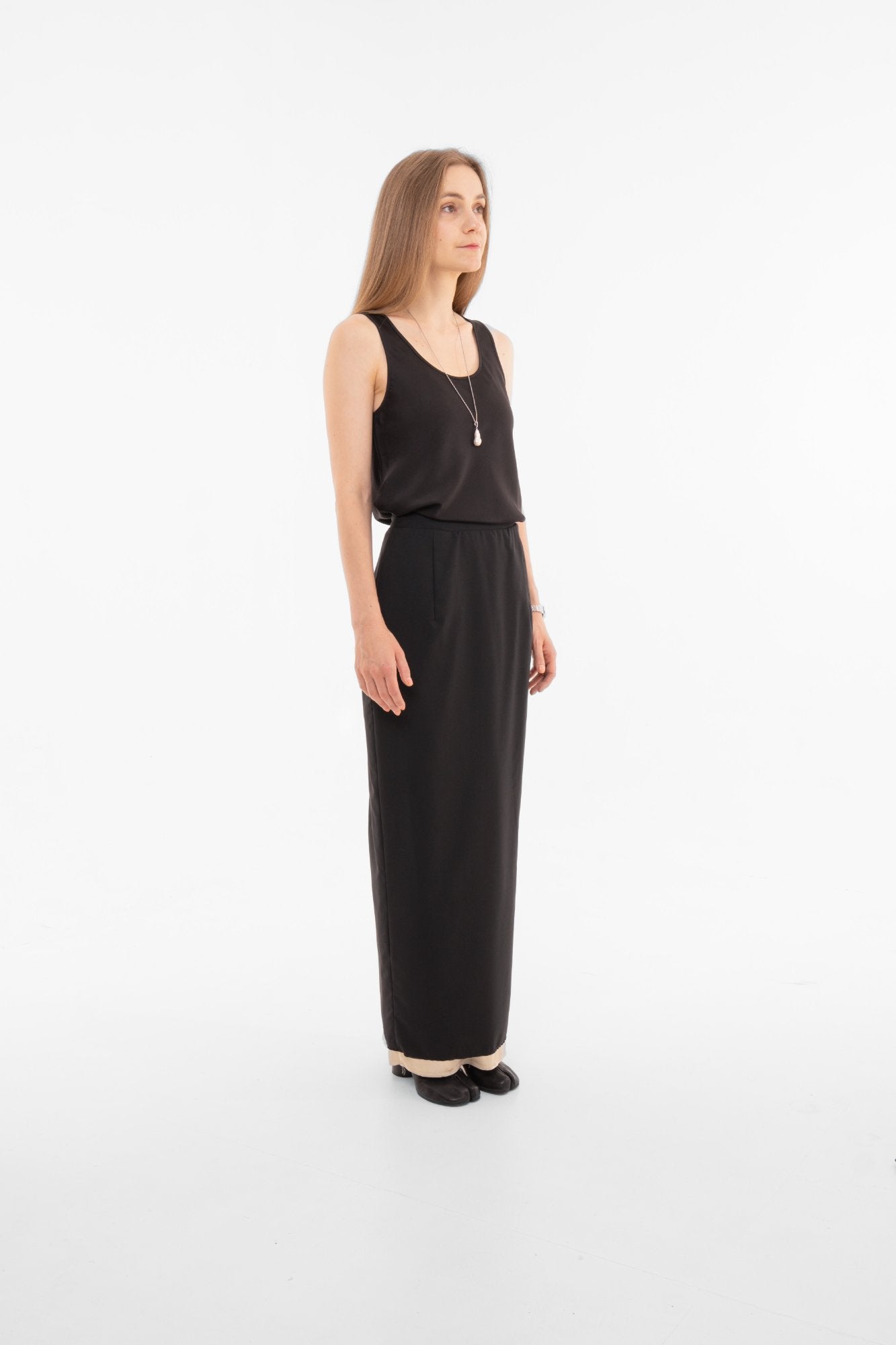 Side profile of high-waist black pencil skirt with contrast lining and raw-edge hem - minimalist designer piece Made in Spain