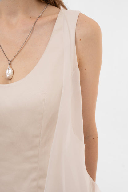 Close-up detail of beige cotton blouse with asymmetric organza panel and deep scoop neckline