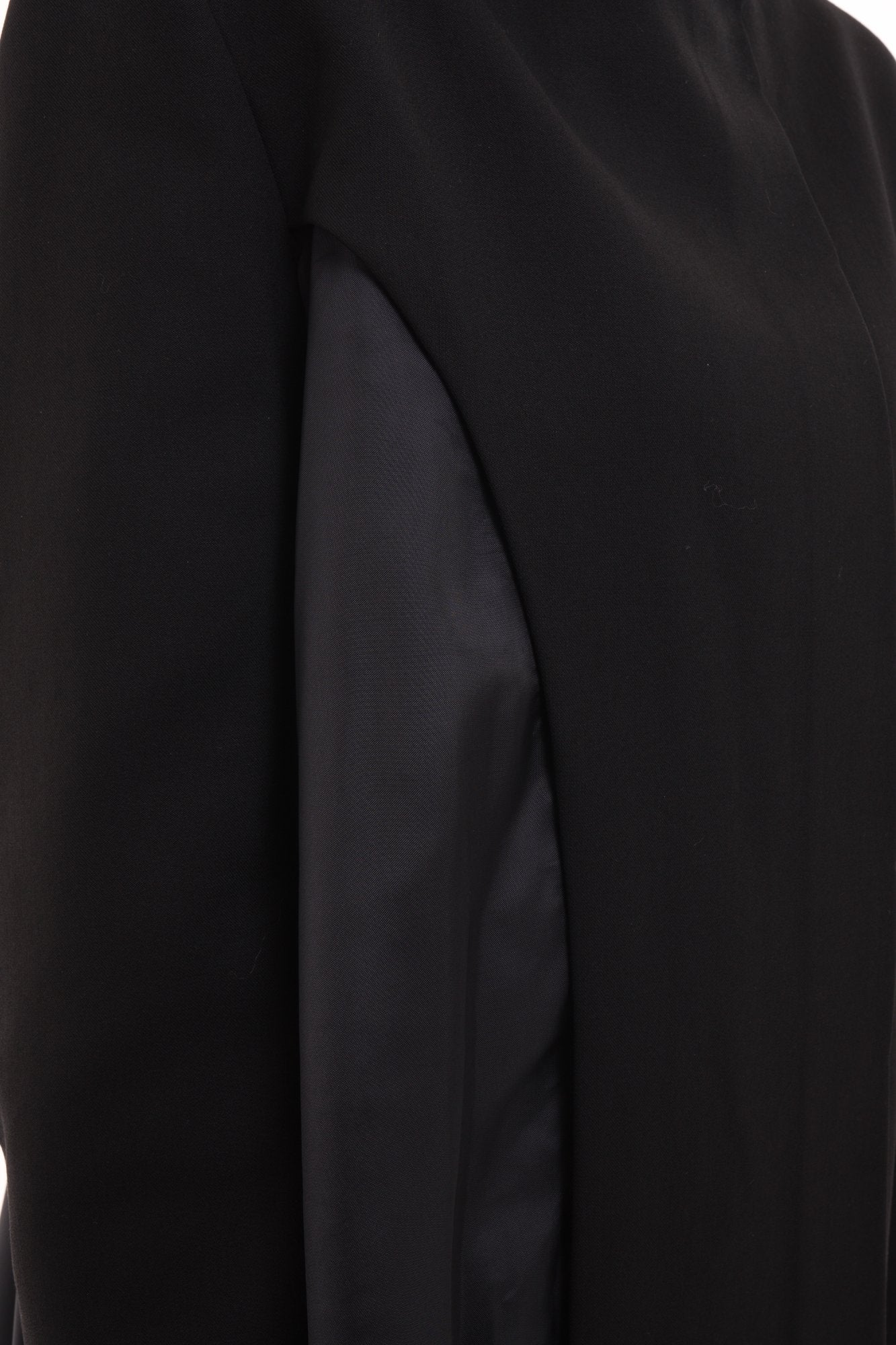 Closeup of oversized black stand-collar blazer showing asymmetric cutout
