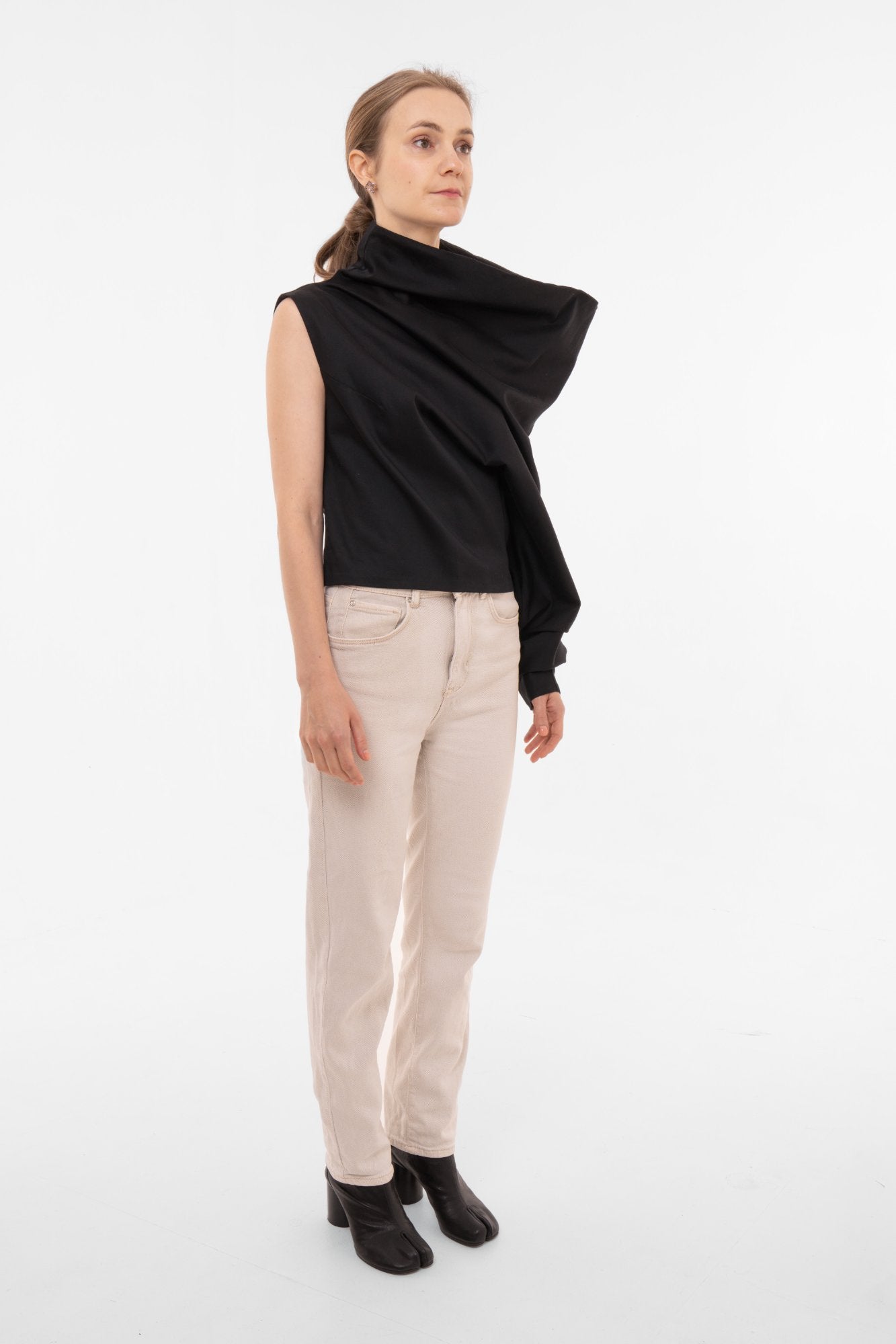 Woman wearing a black sleeveless top and beige pants on a white background