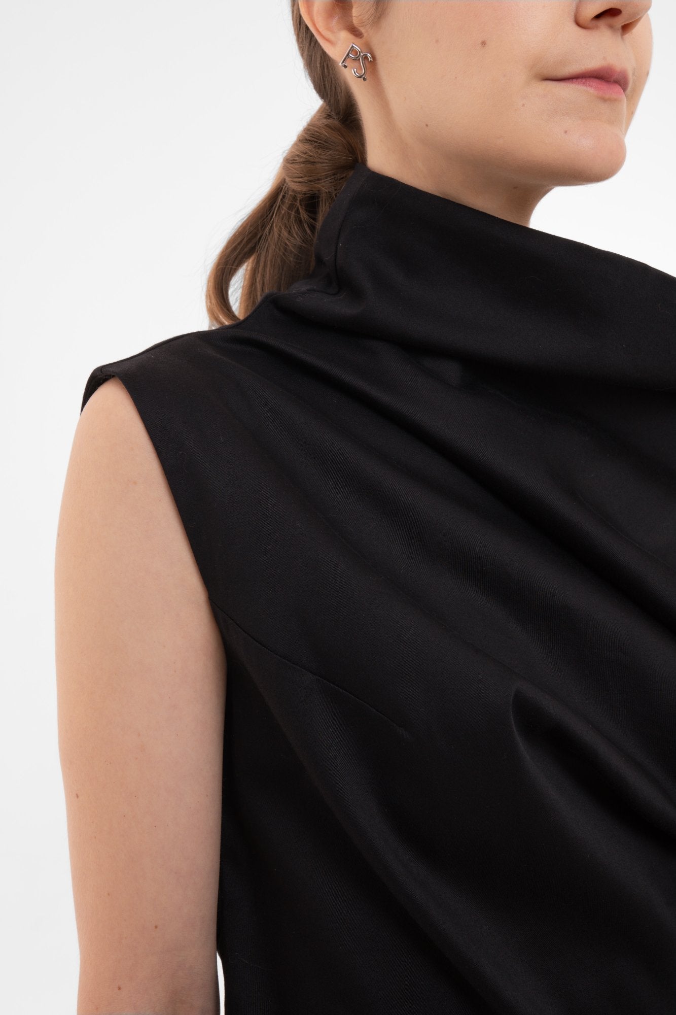 Person wearing a black sleeveless top against a white background