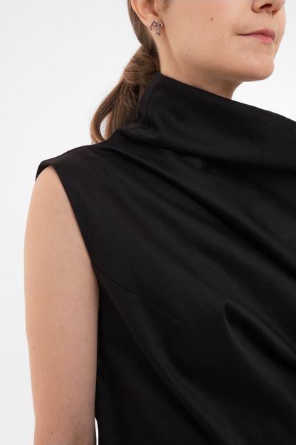 Person wearing a black sleeveless top against a white background