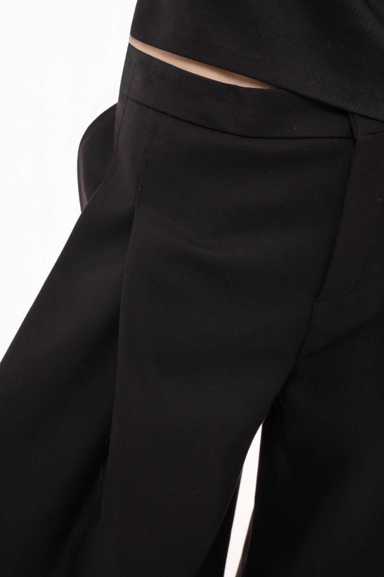 Close-up detail of high-waist wide-leg trousers with deep front pleats and zip fly closure
