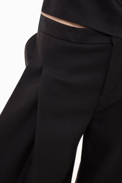 Close-up detail of high-waist wide-leg trousers with deep front pleats and zip fly closure