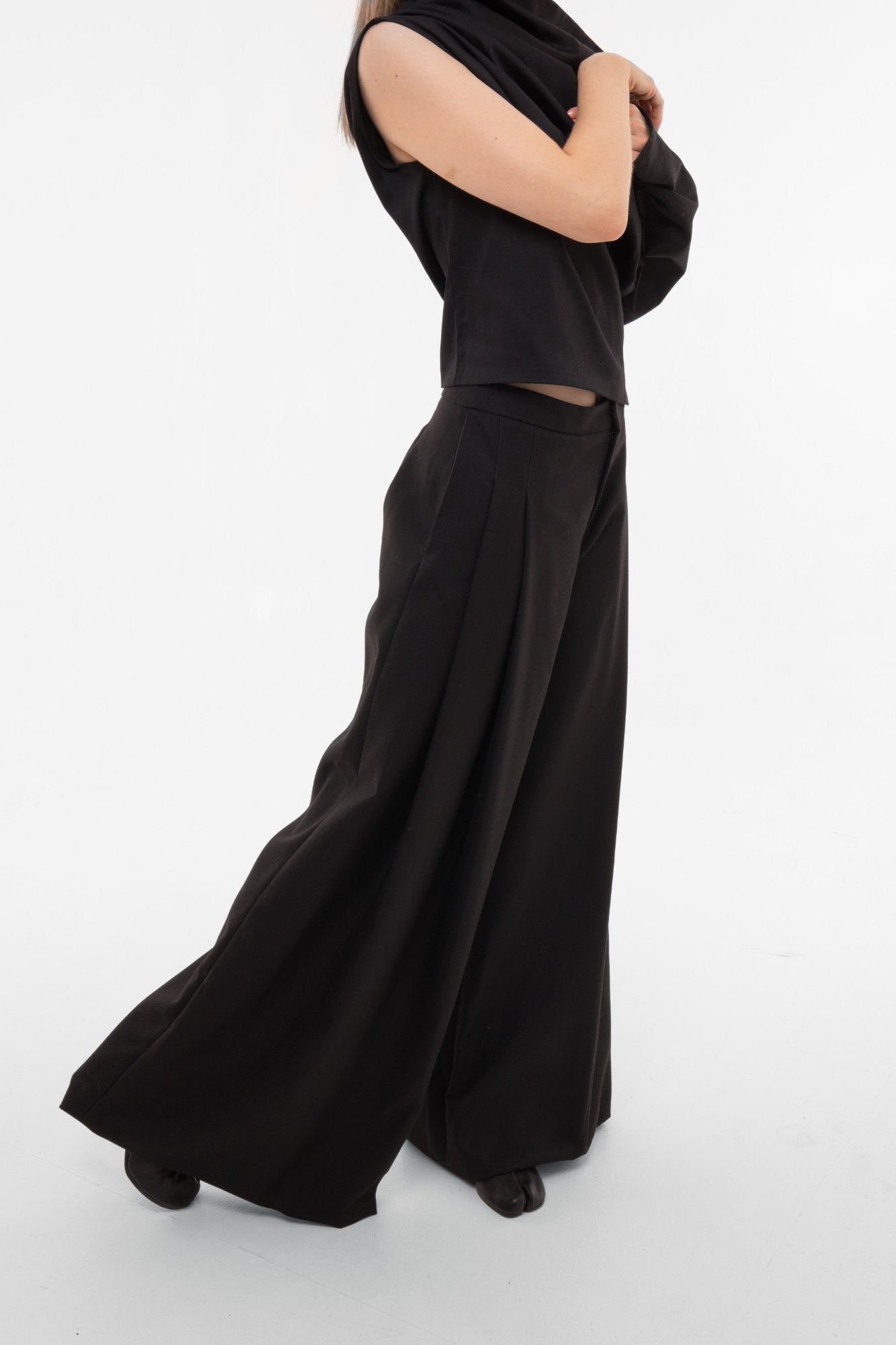 Black wide-leg pleated trousers in motion showing fluid drape and palazzo silhouette 