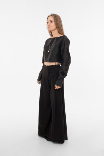 Side profile of black wide-leg pleated trousers with dramatic fluid silhouette - designer pants by Sazha