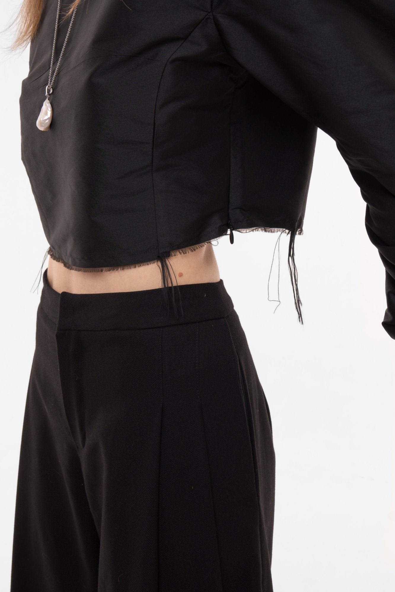 Close-up of black cropped top raw-edge hem and silk taffeta texture