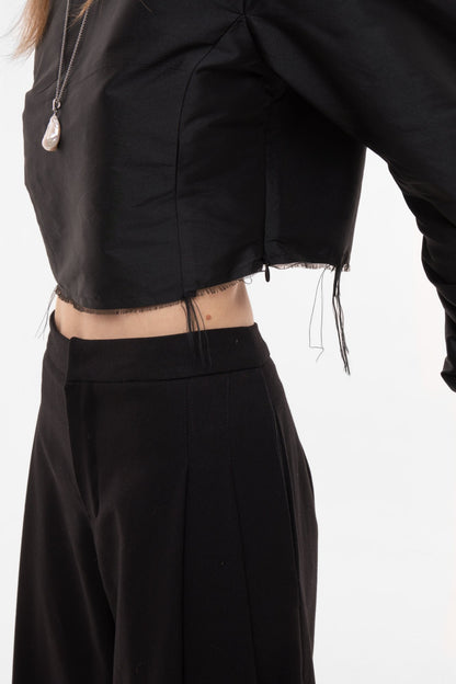 Close-up of black cropped top raw-edge hem and silk taffeta texture