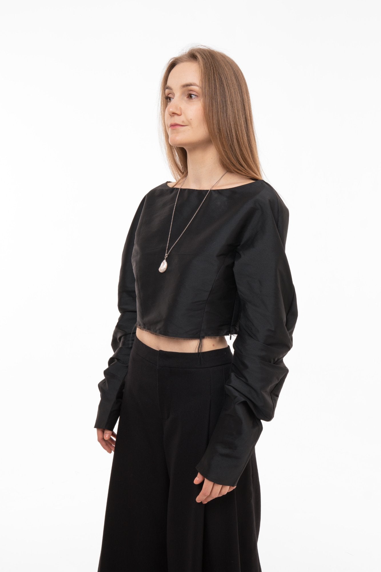 Black silk taffeta cropped top with dramatic sleeves styled with wide-leg trousers - side view 