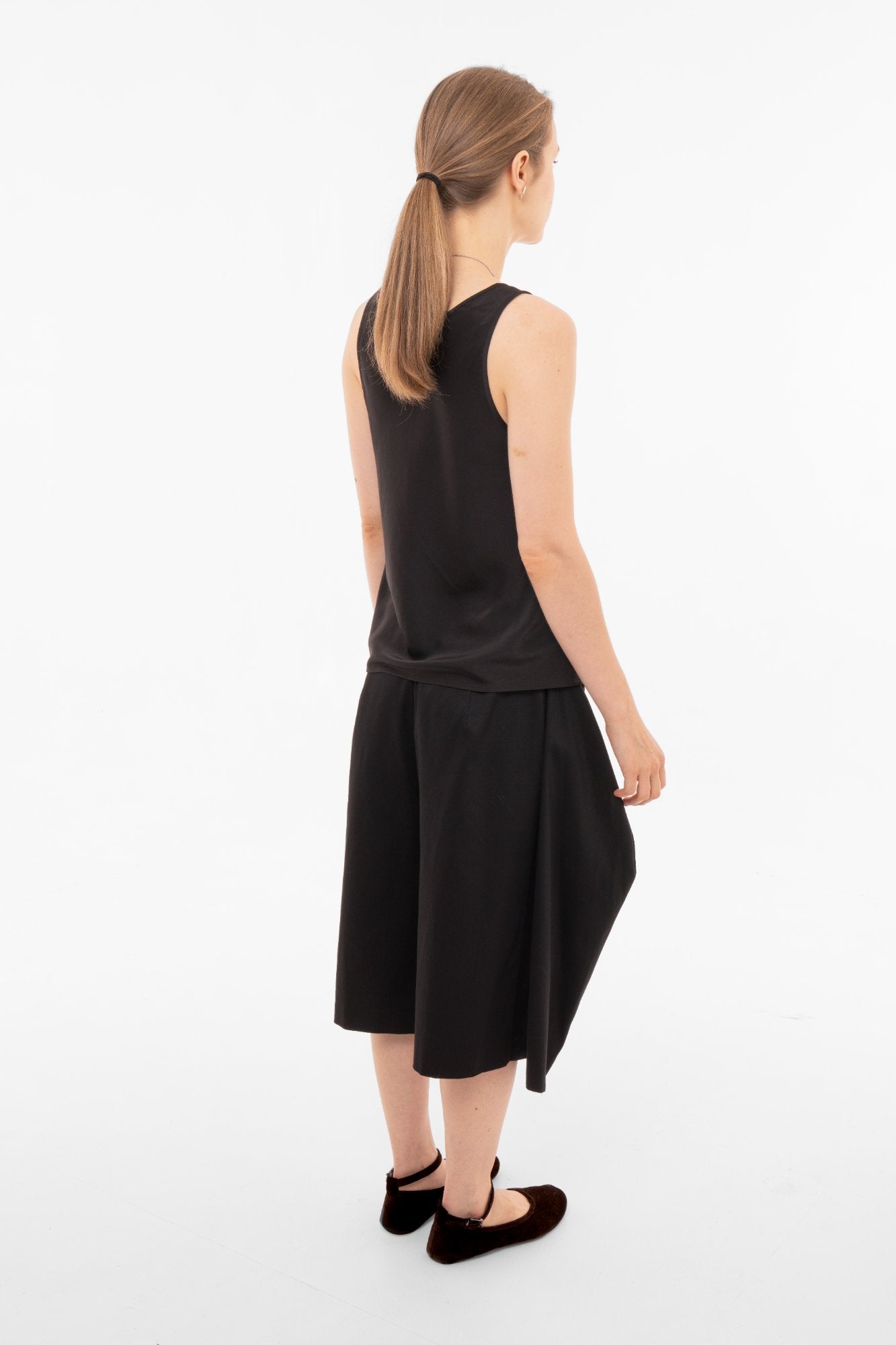 Woman wearing a black sleeveless top and black wide-leg pants on a white background back view - Sazha Barcelona