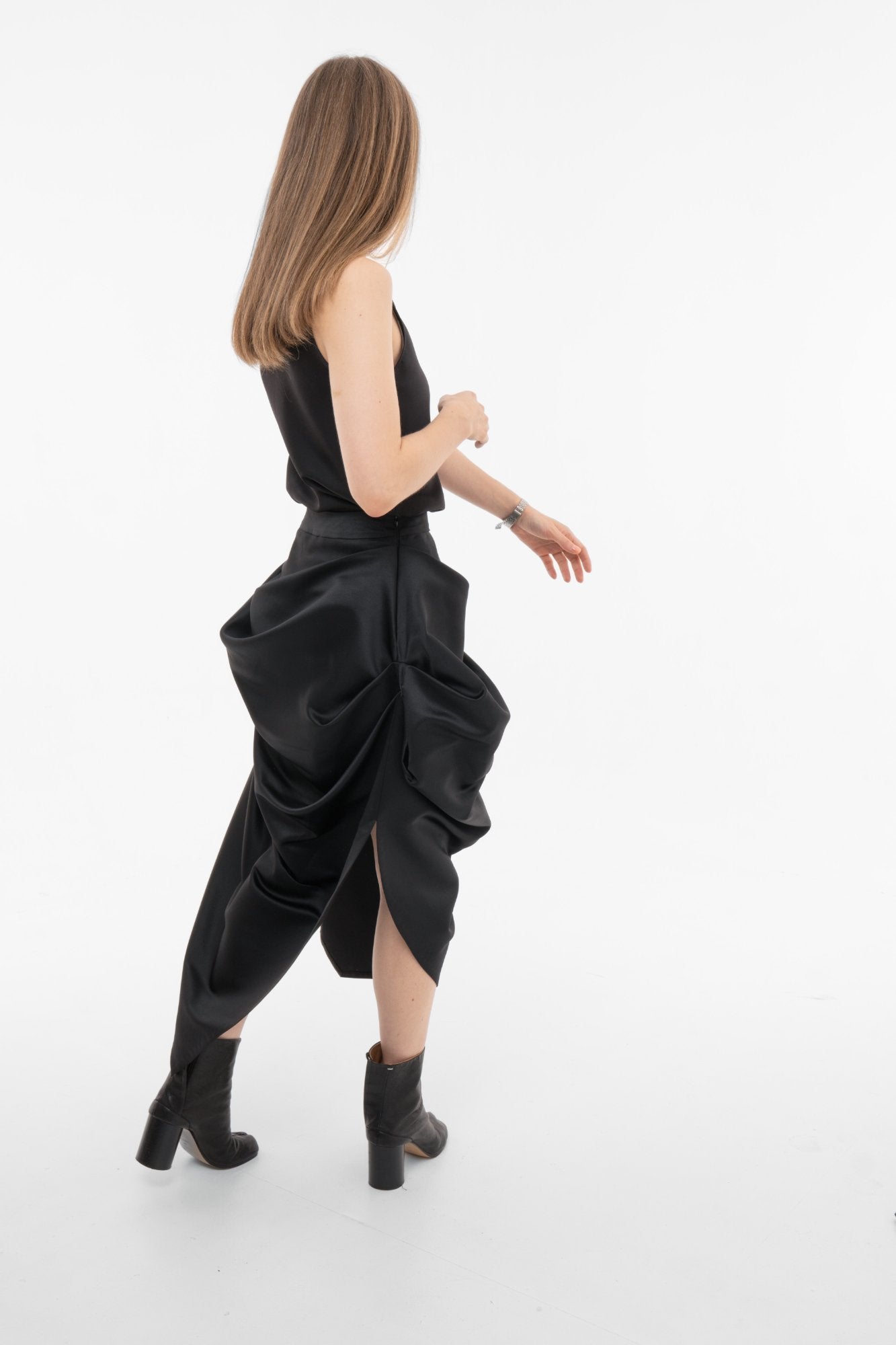 Side view of black maxi skirt showing asymmetric hemline and architectural draping"