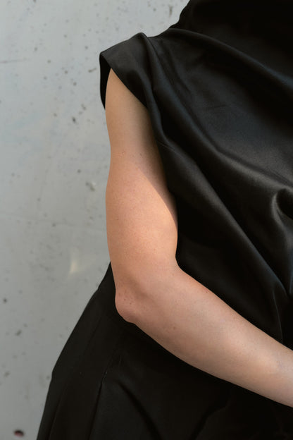 Close-up on the tailored cut of a black asymmetric fashion top