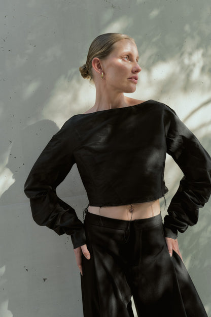 Front view of a boxy black silk taffeta cropped top with voluminous long sleeves and raw-edge hem
