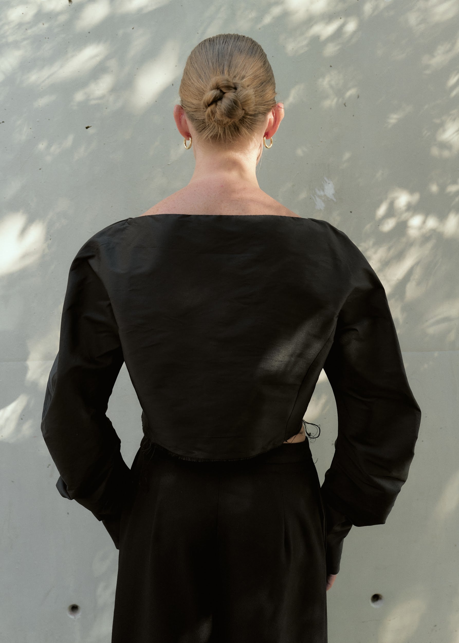 Back view of a black silk taffeta cropped top showing clean lines and raw-edge hem