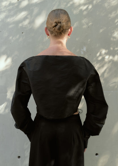 Back view of a black silk taffeta cropped top showing clean lines and raw-edge hem